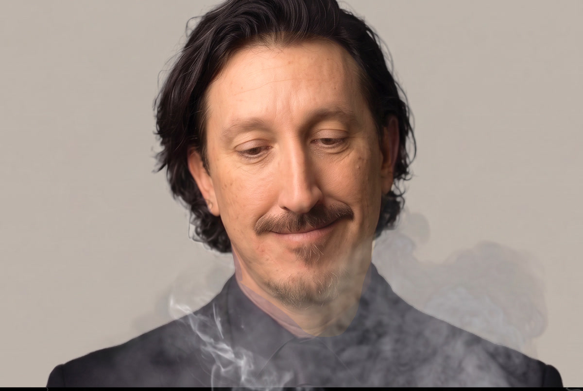 Anthony Hartman in a dark suit, eyes closed, smoke drifting across a warm grey studio backdrop
