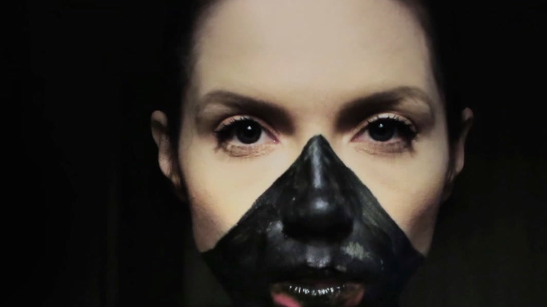 Agata Alexander facing camera, black paint across her nose and mouth, colour dripping down